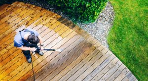 man cleaning deck with a pressure washer